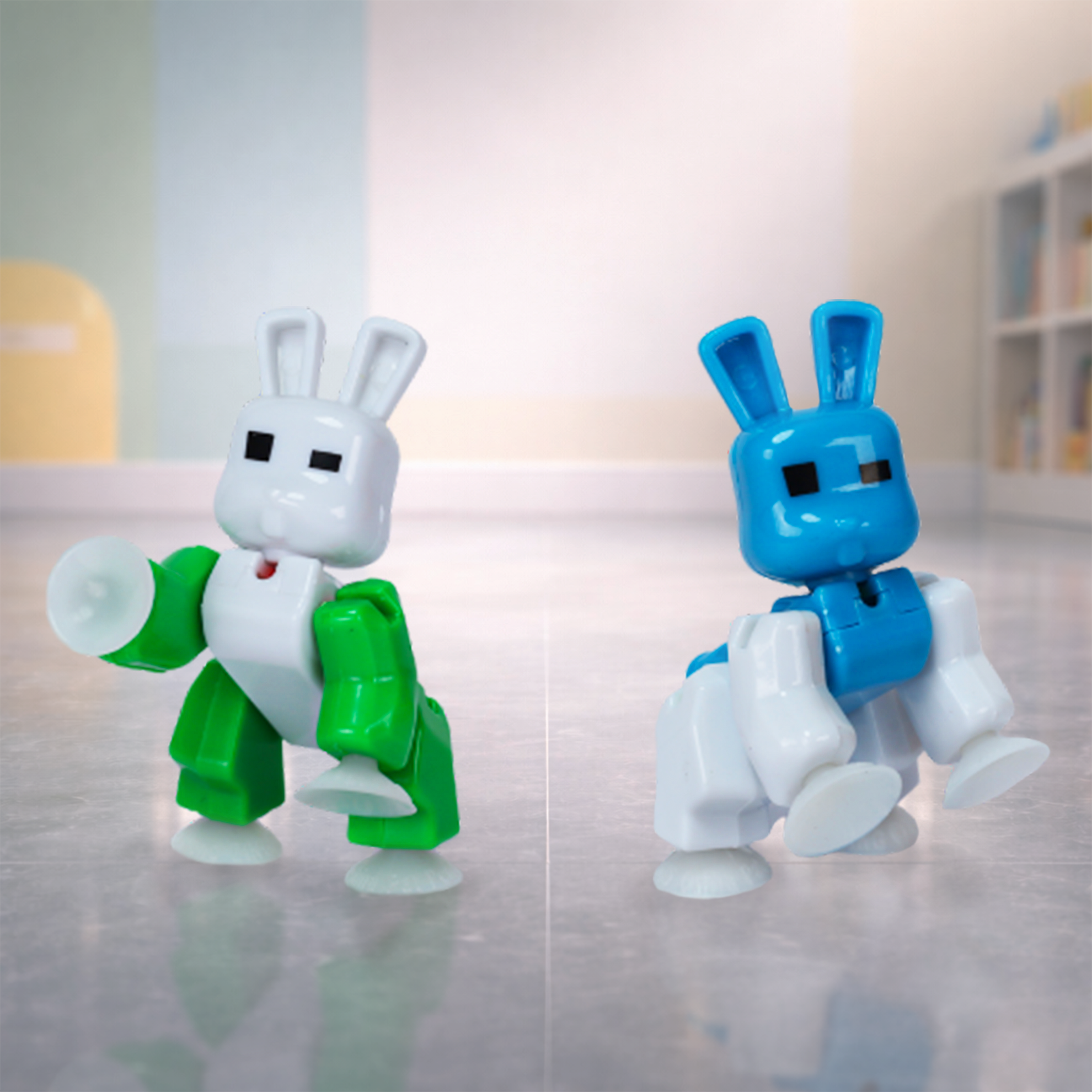 Green and blue BunnyBot figures posed on smooth surface with suction cup feet